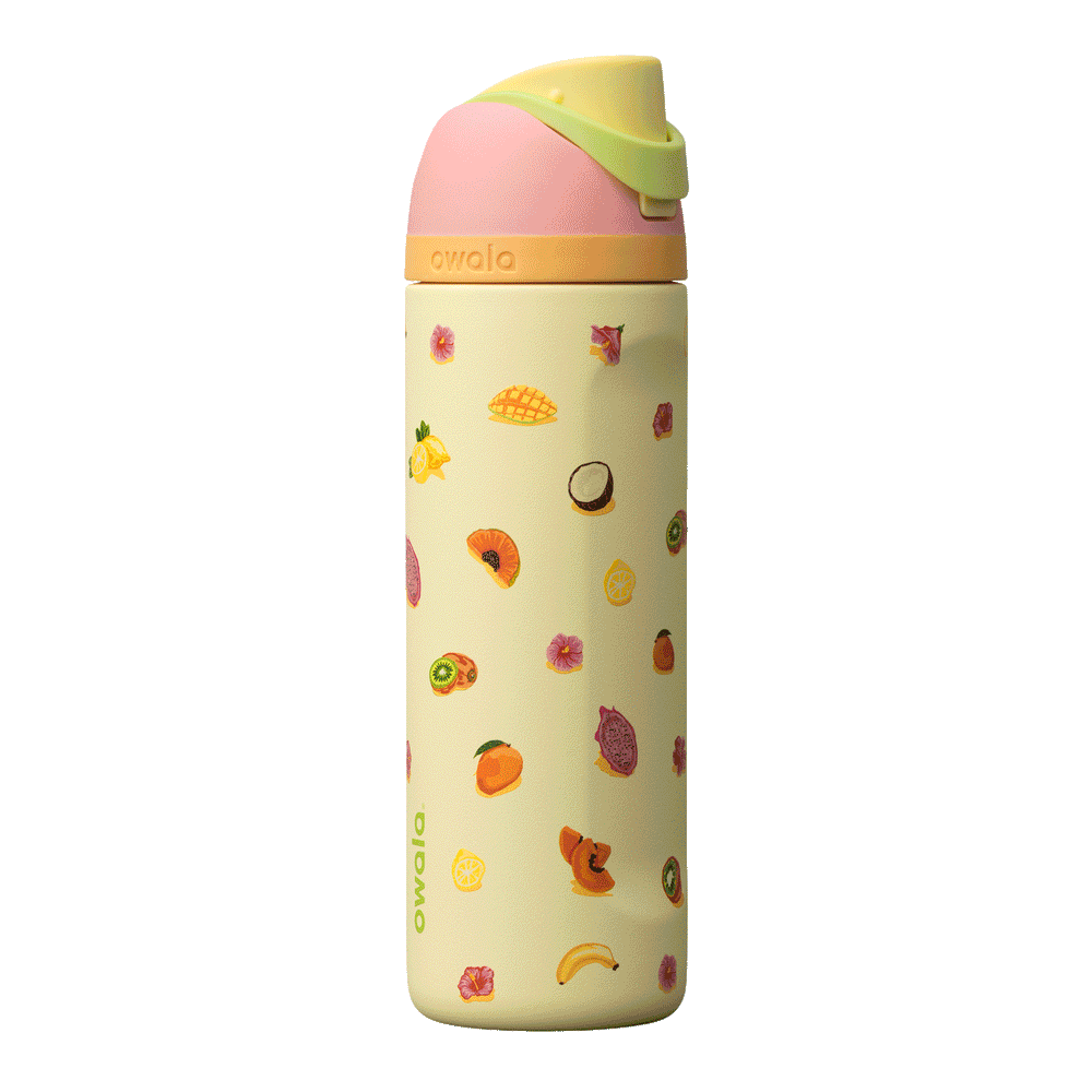 Owala Birthday Bash 24oz FreeSip Just Ripe; soft pale yellow body covered with colorful tropical fruit illustrations — mangoes, pineapples, and papayas — with a coral-pink flip cap