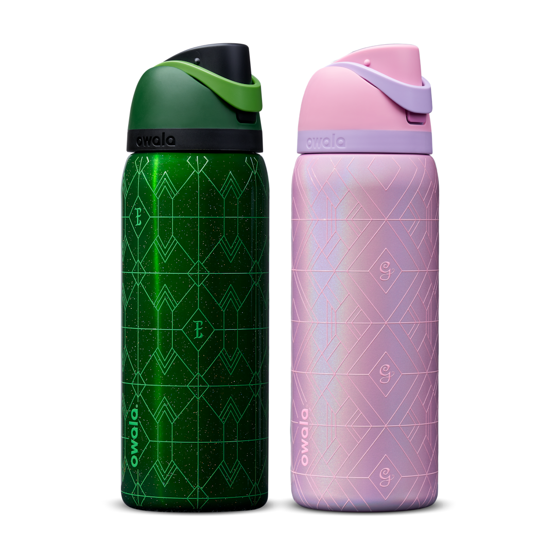 Owala Wicked 32oz FreeSip bundle showing two bottles side by side — deep emerald green Elphaba edition with geometric diamond-pattern texture and dark green flip cap, and shimmery iridescent lavender-pink Glinda edition with pink flip cap Main image