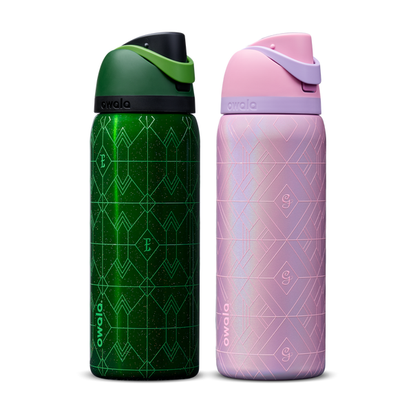 Owala Wicked 32oz FreeSip bundle showing two bottles side by side — deep emerald green Elphaba edition with geometric diamond-pattern texture and dark green flip cap, and shimmery iridescent lavender-pink Glinda edition with pink flip cap
