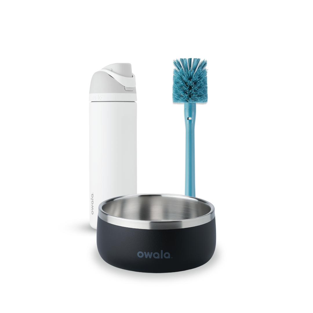 Owala FreeSip and Pet Bowl Bundle showing a white FreeSip bottle, a teal-handled bottle brush with blue bristles, and a dark charcoal stainless steel pet bowl with white Owala logo Main image